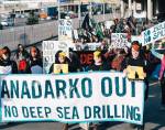 People dressed as penguins march behind an "Anadarko Out! No deep sea drilling" banner.